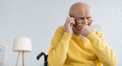 Older man in a wheelchair crying whilst on the phone